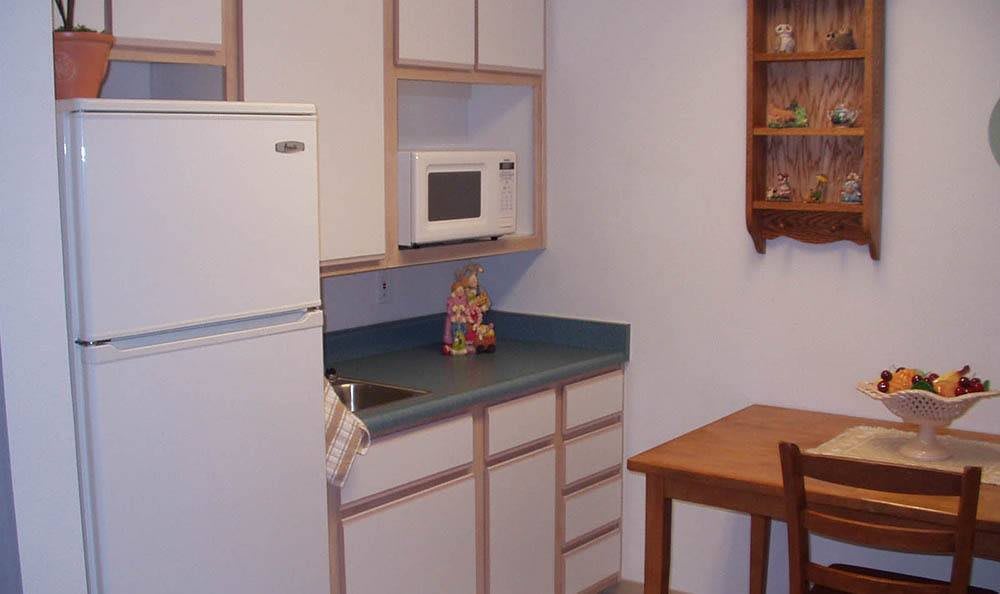 A small kitchen area with a refrigerator, microwave, sink, and wooden table.