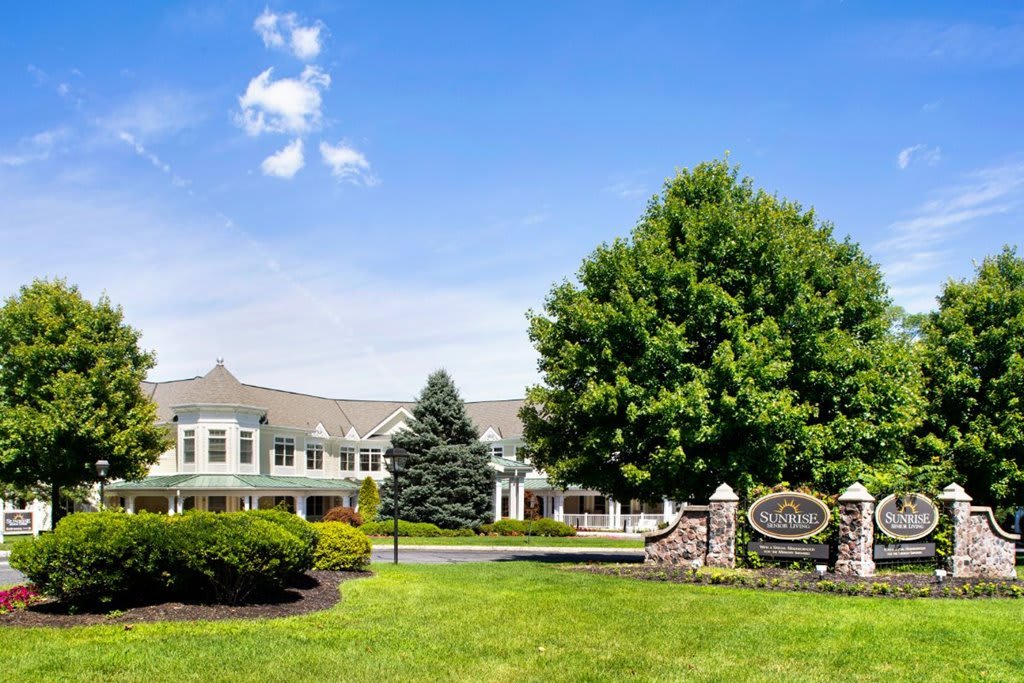 A scenic view of a large building surrounded by lush greenery and a bright blue sky.