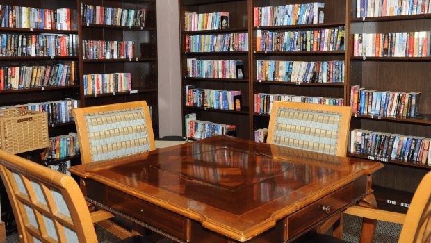 A cozy library space with wooden tables and bookshelves filled with books.