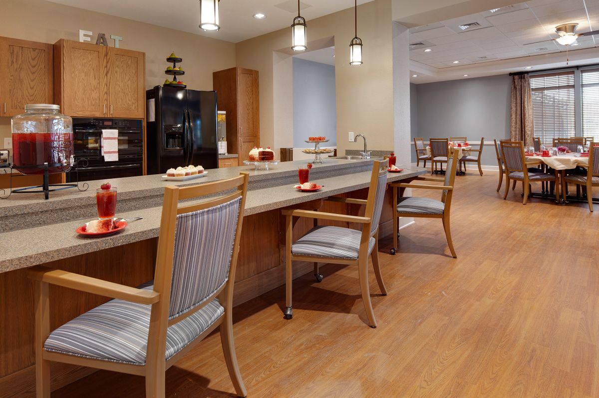 A modern dining area with wooden flooring, comfortable chairs, and pendant lighting.