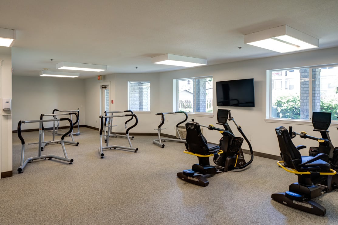 A modern gym with various fitness equipment including treadmills and a stationary bike.