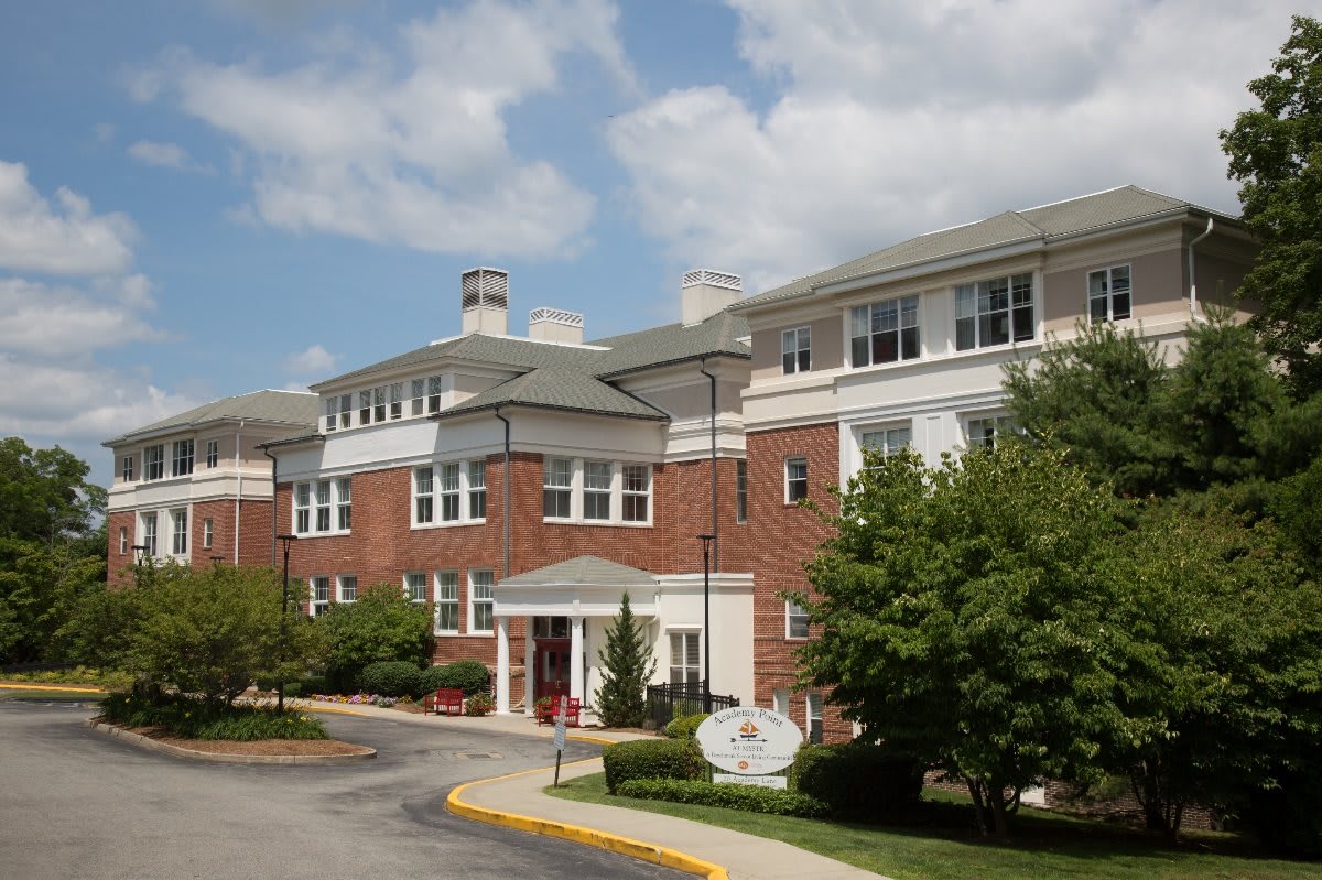 A brick residential building with landscaping and a cloudy sky.