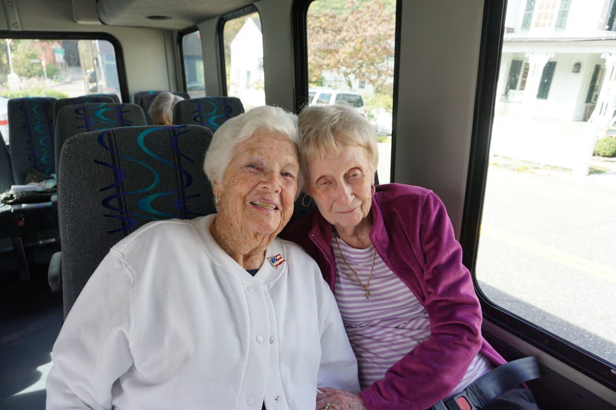Two elderly women sharing a joyful moment on a bus.