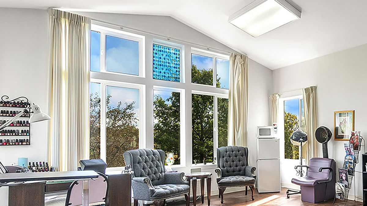 A bright living room with large windows, two armchairs, and sunlit surroundings.