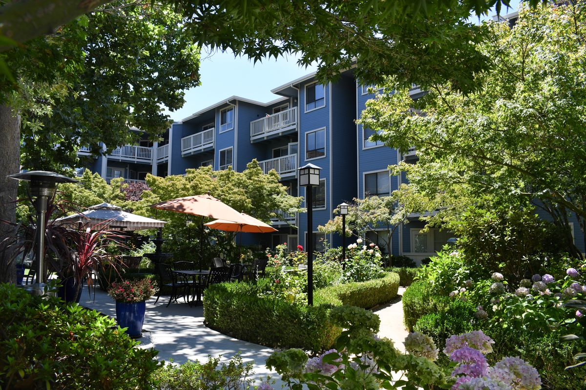A peaceful apartment complex with a well-maintained garden and outdoor seating areas.