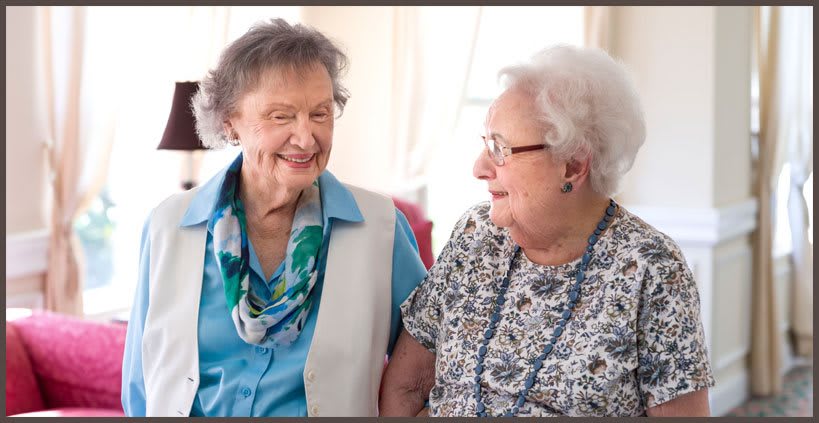Two elderly women smiling and engaging in conversation.