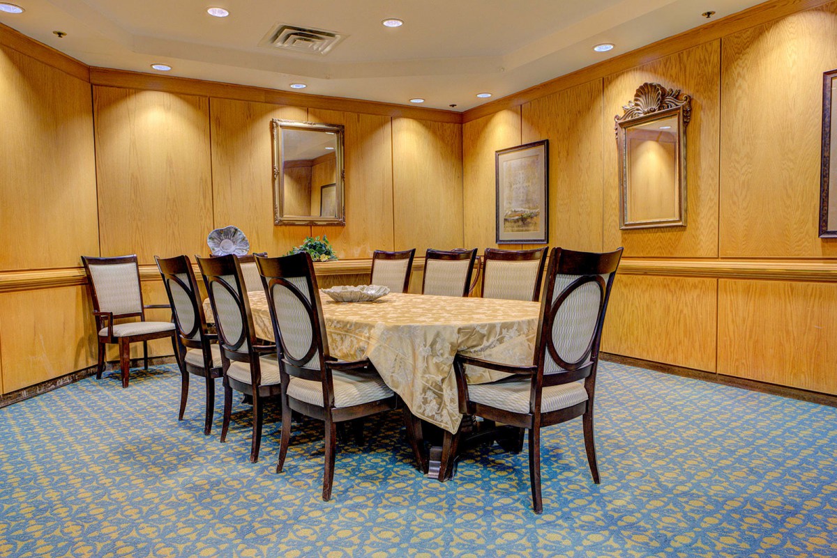 Elegant dining room with a large table and chairs, featuring mirrors and decorative elements.