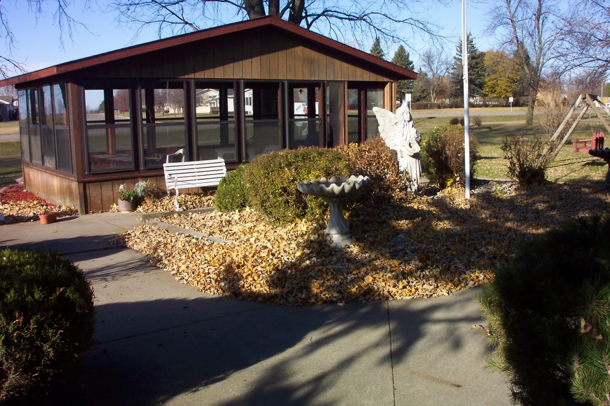A peaceful garden scene with a bench and statue near a gazebo in autumn.
