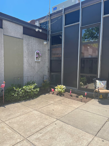 A view of a modern building corner with a small garden and patio area.