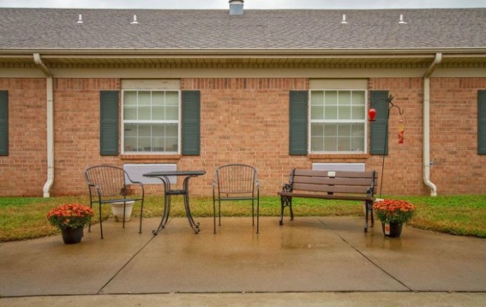 A small patio area with outdoor furniture in front of a brick house.