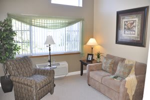 A cozy living room with a sofa, armchair, and two lamps by the window.