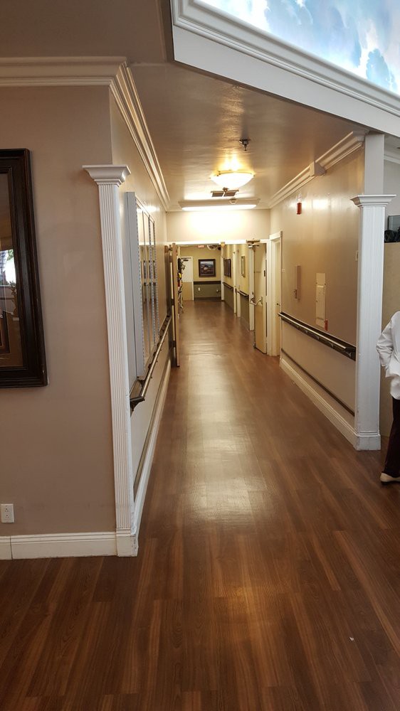 A long, well-lit hallway with wooden floors and handrails on the walls.
