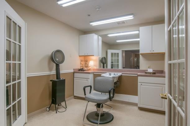 A well-lit hair salon with a styling chair, mirror, and hair dryer.