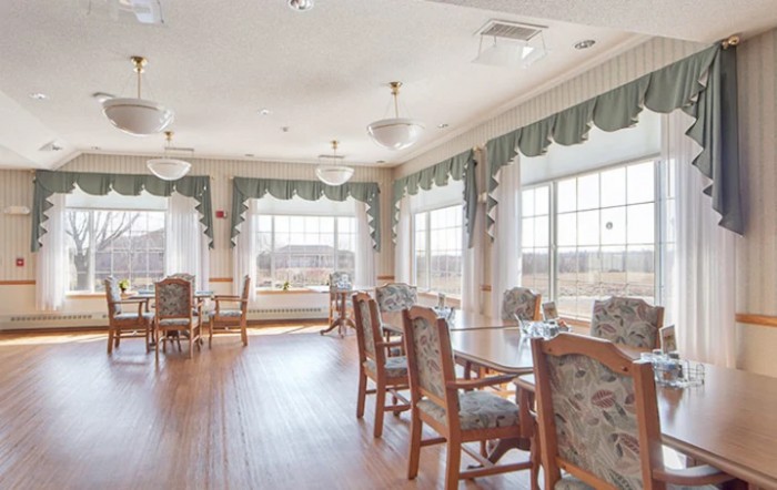 A bright and spacious dining room with wooden floors, large windows, and elegantly decorated tables and chairs.
