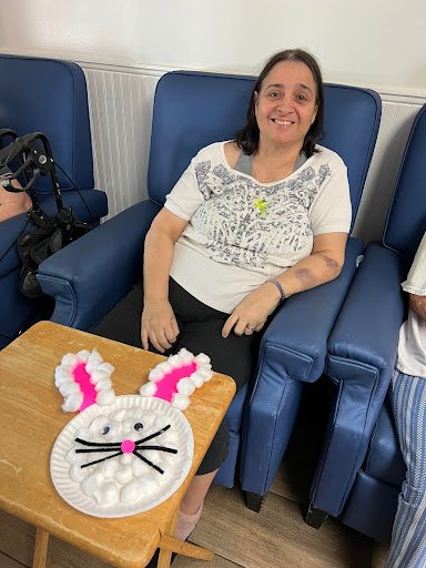 A woman proudly displays her Easter-themed craft, featuring a bunny face made of cotton and colorful details.