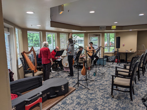 A group of musicians rehearsing with various instruments in a cozy indoor space.