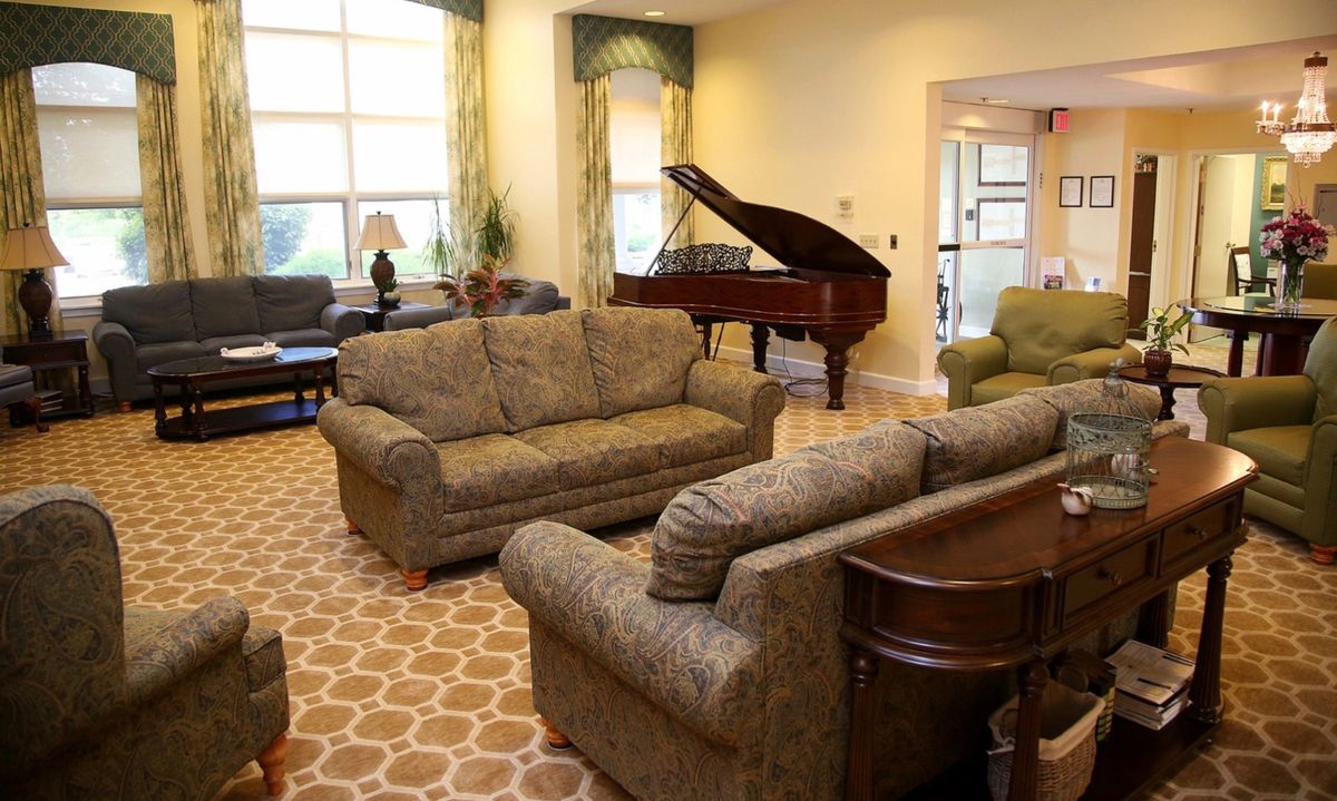 A cozy living room featuring a grand piano and comfortable sofas.