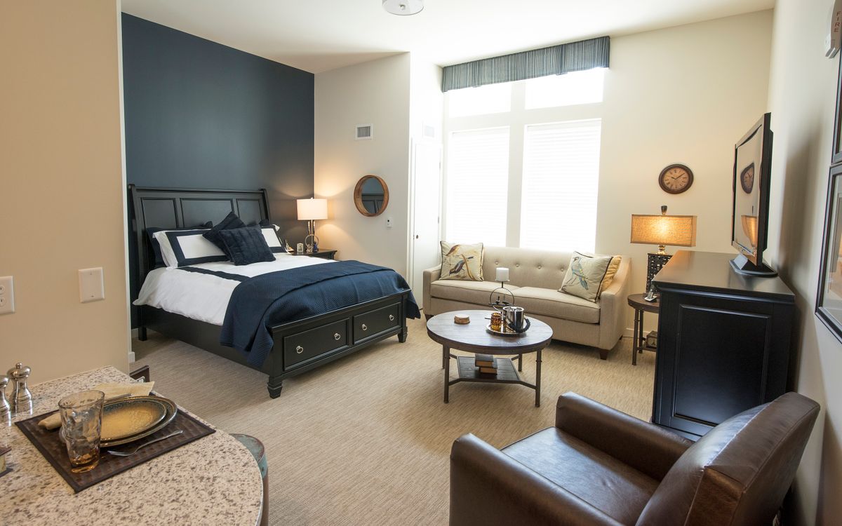 A modern bedroom with elegant furniture, featuring a bed, sofa, and table lamps.