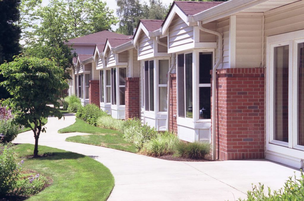 A row of suburban houses with brick exteriors and neatly landscaped pathways.
