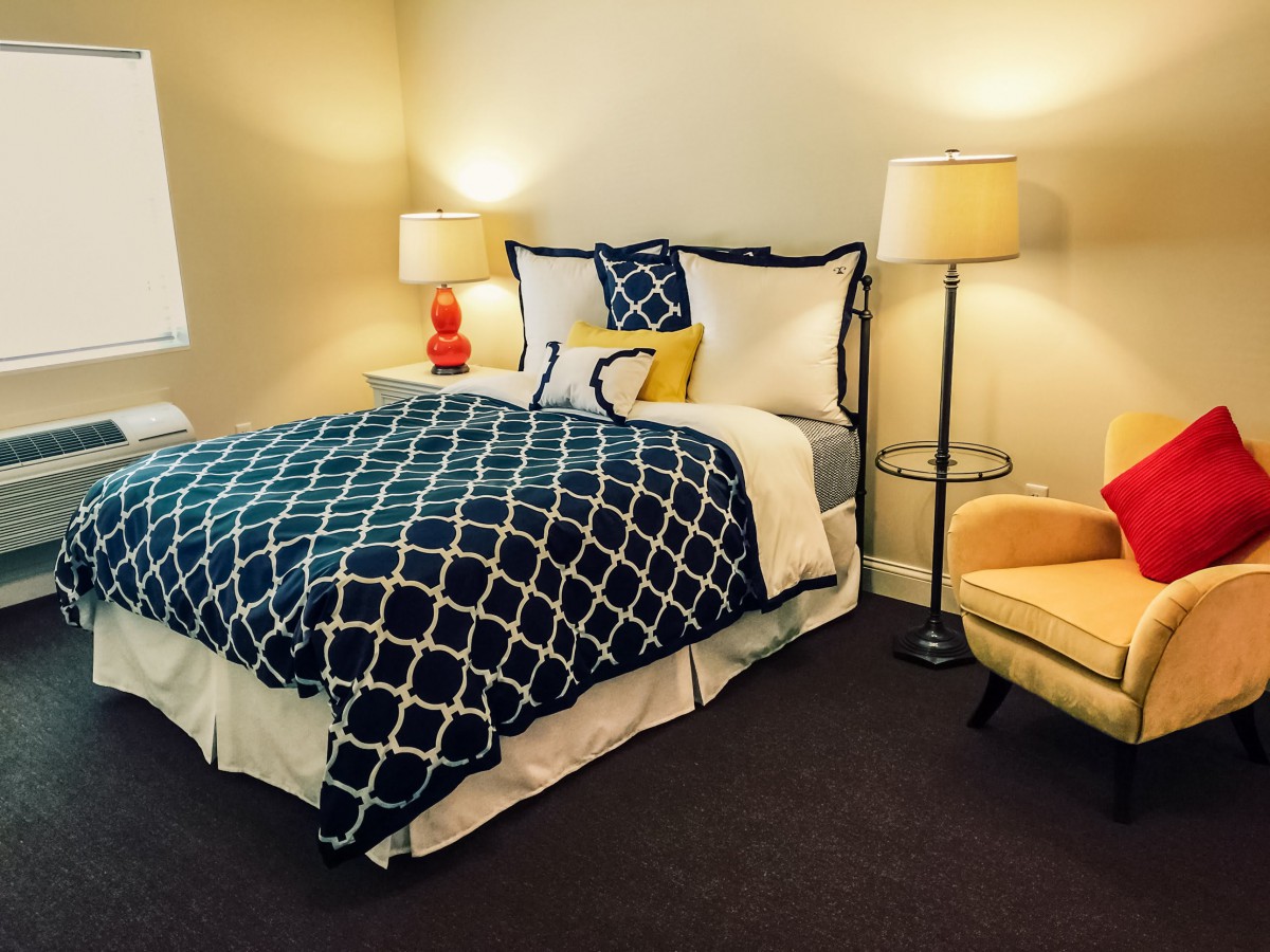 A cozy bedroom with a stylish bed, vibrant lamps, and comfortable seating.