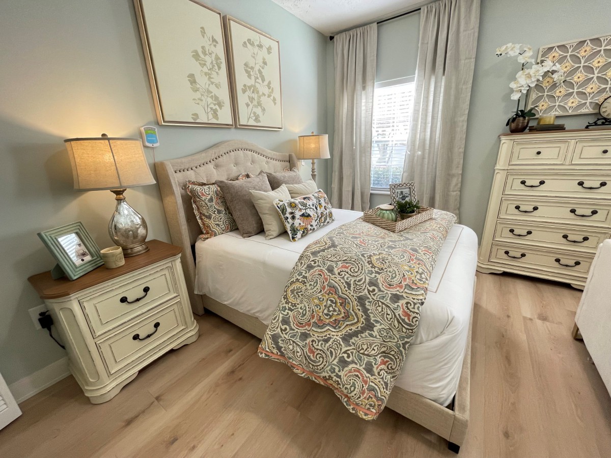 A cozy bedroom with traditional decor, featuring a bed with decorative pillows, nightstands, and soft lighting.