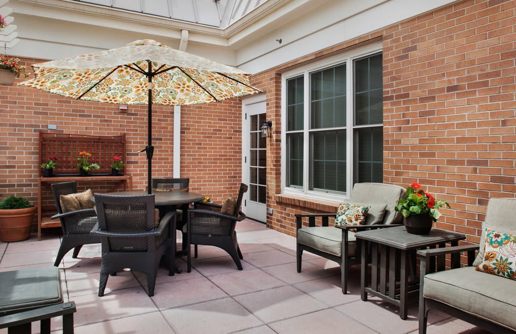 A cozy patio with outdoor furniture and a large umbrella against a brick wall.