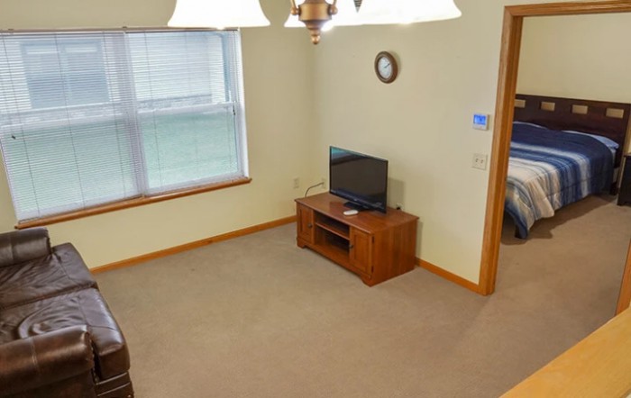 A simple living room with a television, clock, and large window.