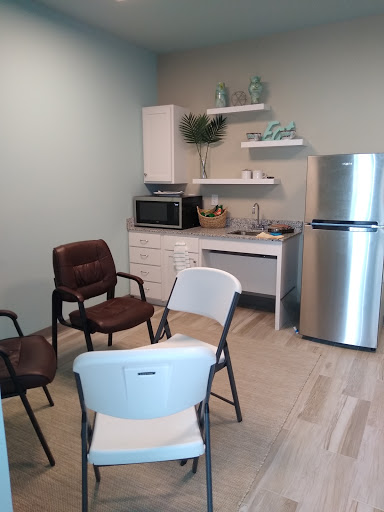 A cozy, well-lit room featuring a small kitchenette with seating arrangements.