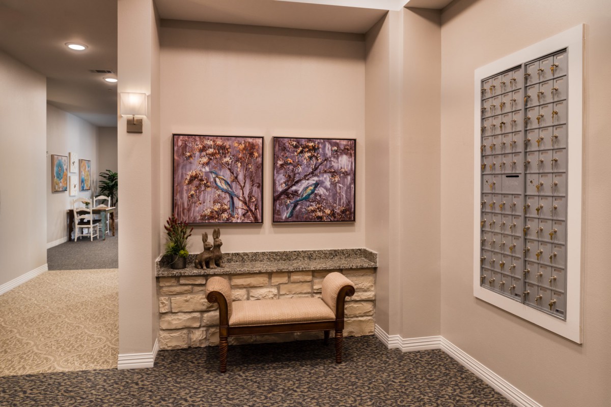 A cozy hallway featuring a cushioned bench, two wall paintings, and decorative elements.