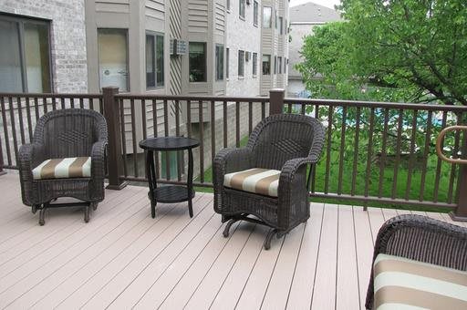 An outdoor patio with wicker chairs and a small table on a residential deck.