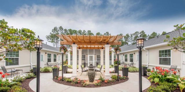 A beautifully designed courtyard with a central pergola surrounded by greenery.