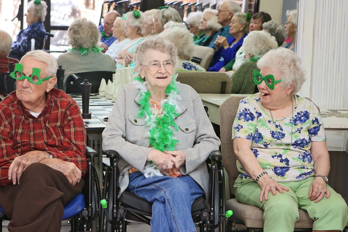 A group of seniors celebrating St. Patrick's Day with festive green decorations and attire.