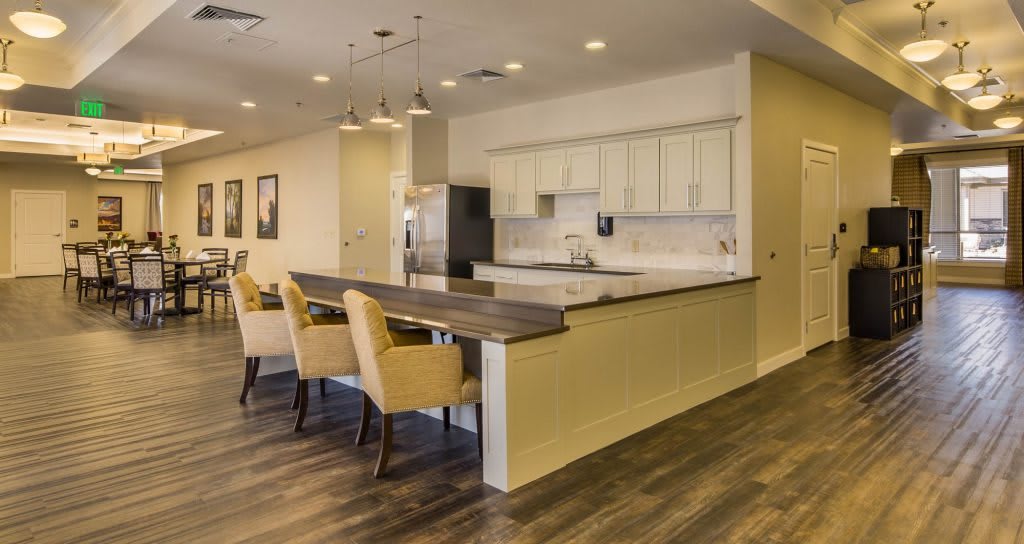 A modern kitchen with a dining area featuring wood flooring, sleek cabinets, and comfortable seating.