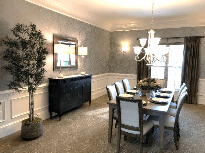Elegant dining room with a large table, chandelier, and decorative wallpaper.