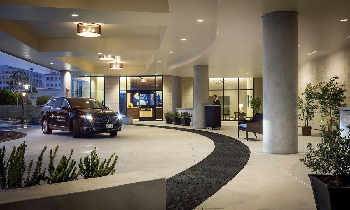 A luxurious hotel entrance at night with a parked car in the driveway.