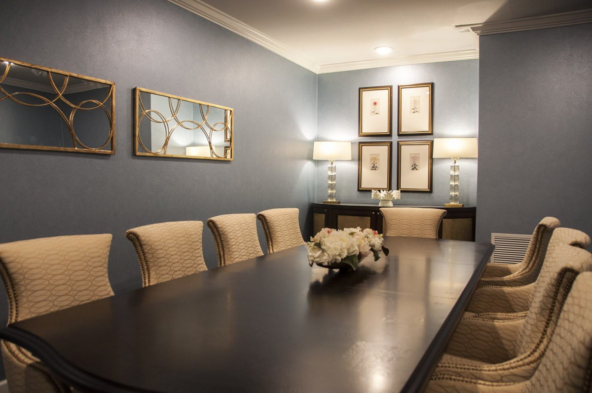 An elegantly decorated dining room featuring a long table, comfortable chairs, wall art, and soft lighting.