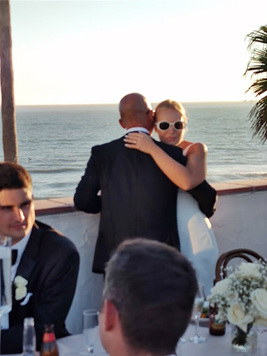 A beautiful moment shared between a bride and groom as they embrace against the backdrop of the ocean at sunset.