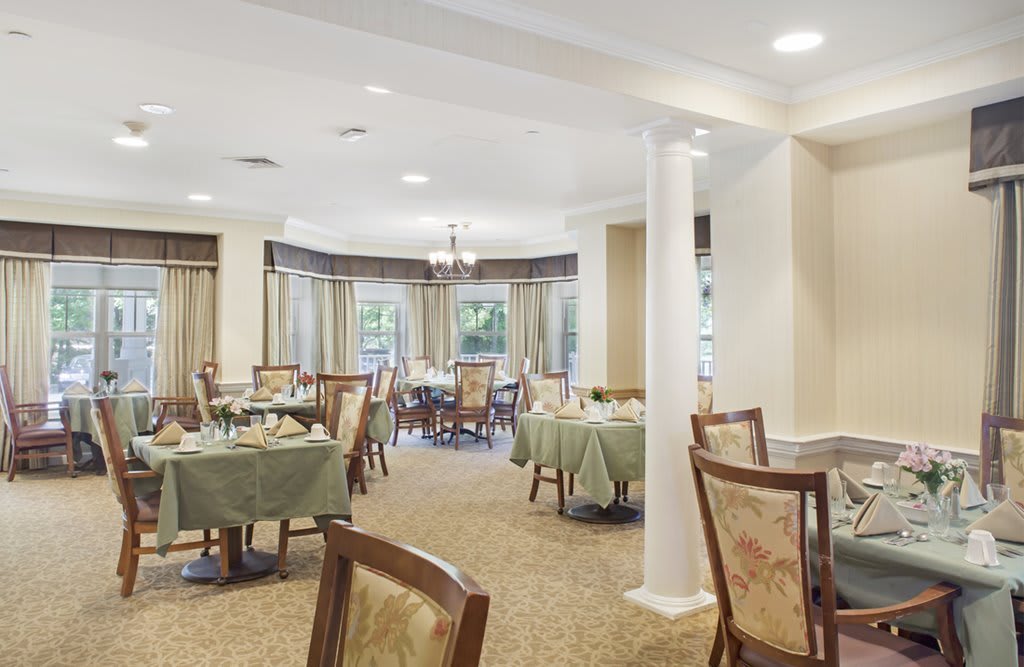 A spacious and elegantly decorated dining room with multiple tables set for guests.