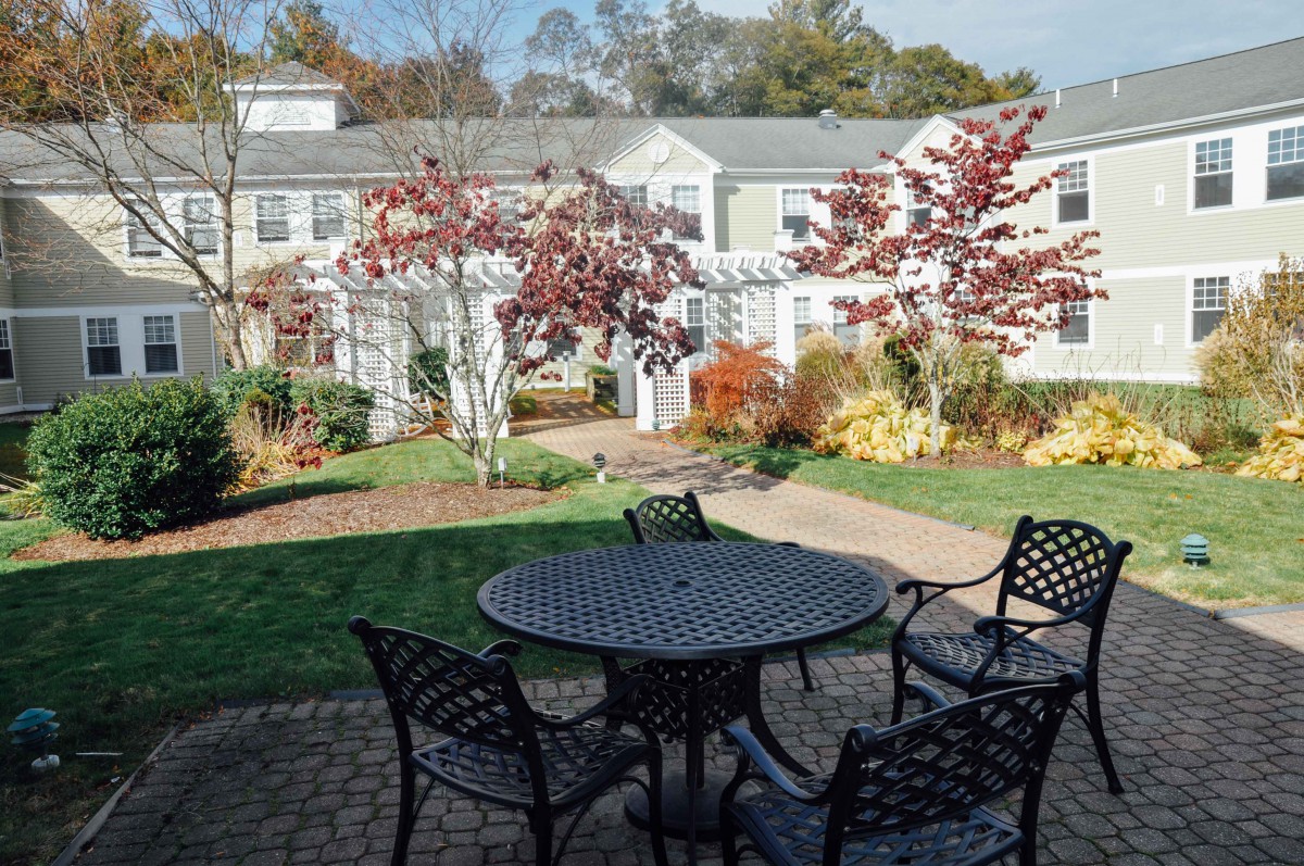 A serene patio area with outdoor furniture surrounded by a garden in autumn.