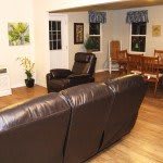 A cozy living room with a leather sofa and adjacent dining area.