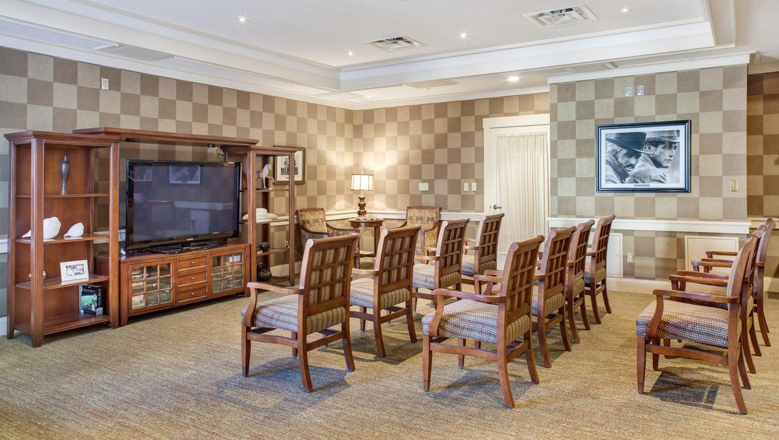 A neatly arranged meeting room with rows of chairs facing a television.