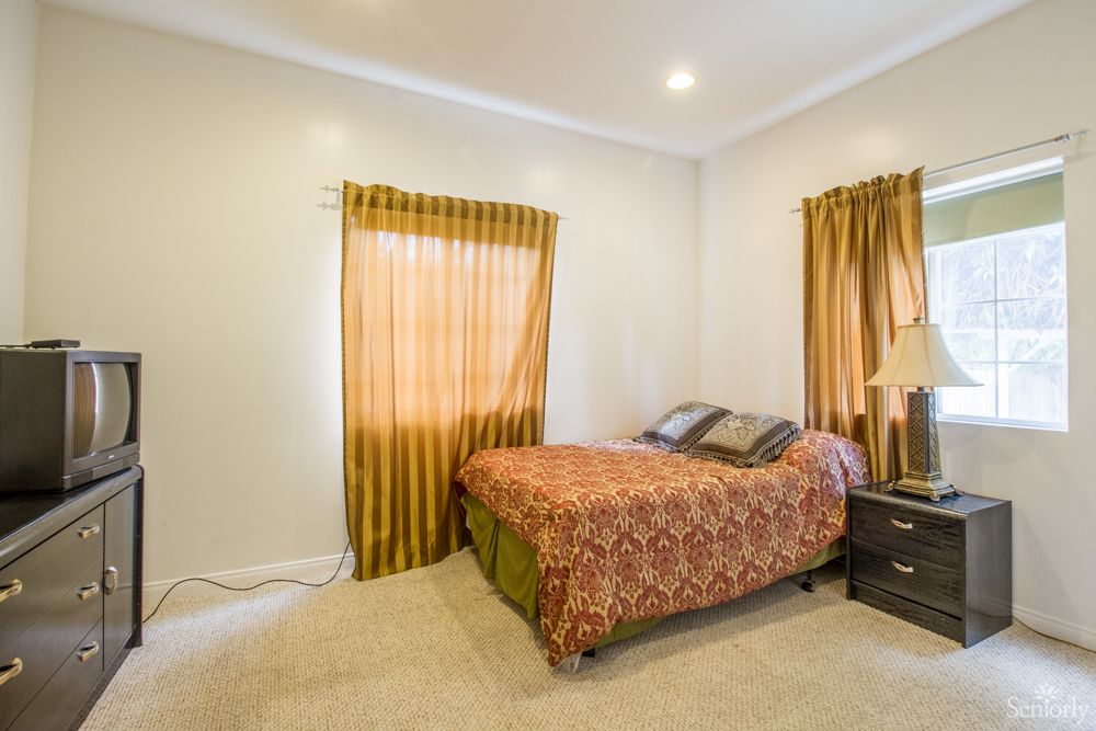 A cozy bedroom with a bed, patterned curtains, and a bedside lamp.