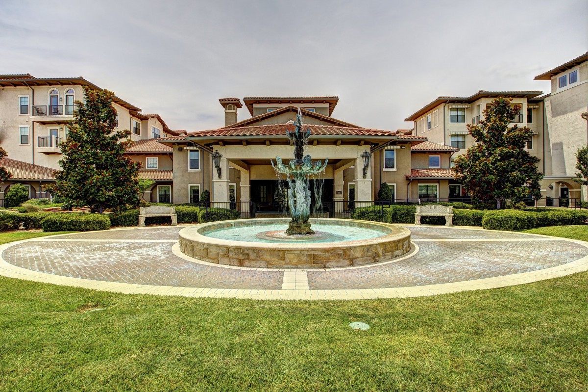 A residential building with a central fountain and landscaped lawn.