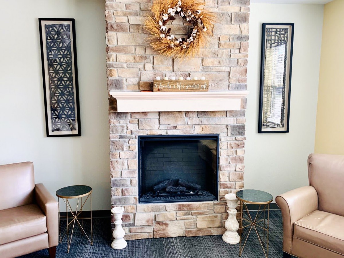 A cozy living room featuring a brick fireplace adorned with a wreath, flanked by two decorative mirrors and side tables.