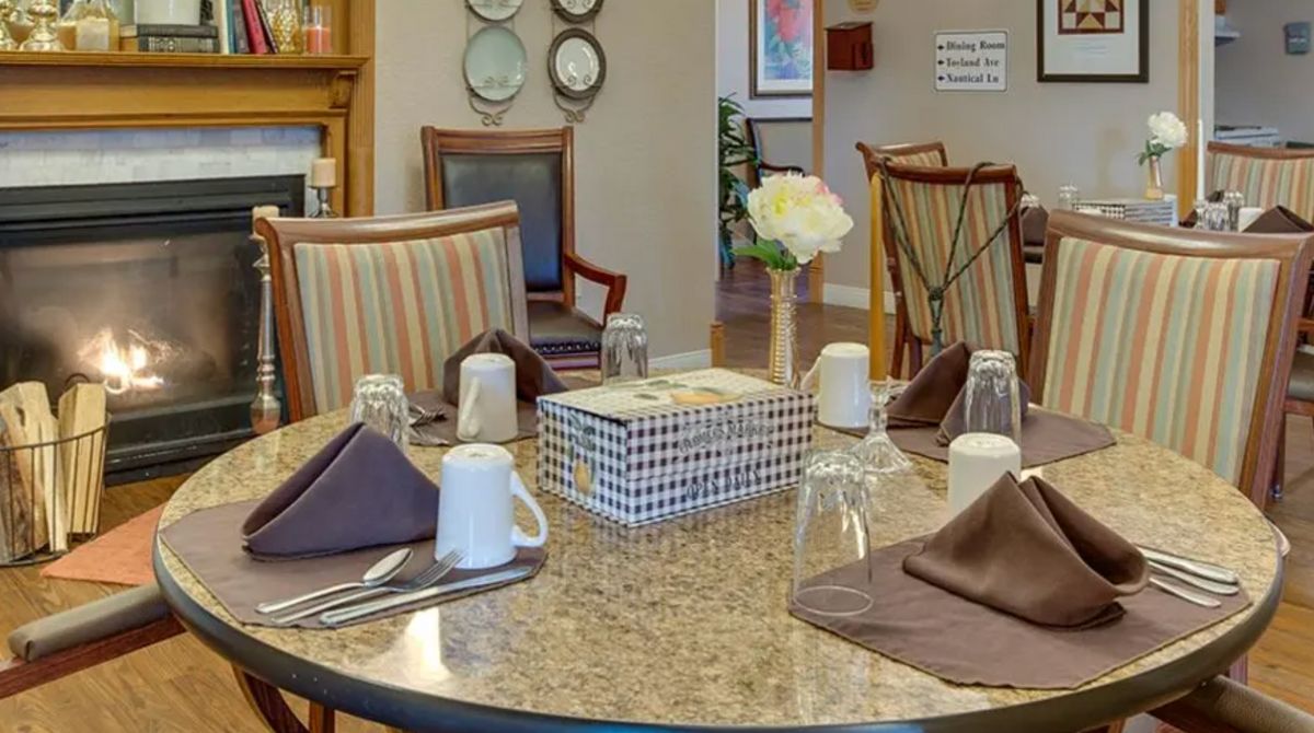 A neatly arranged dining table with napkins, glasses, and a flower vase.