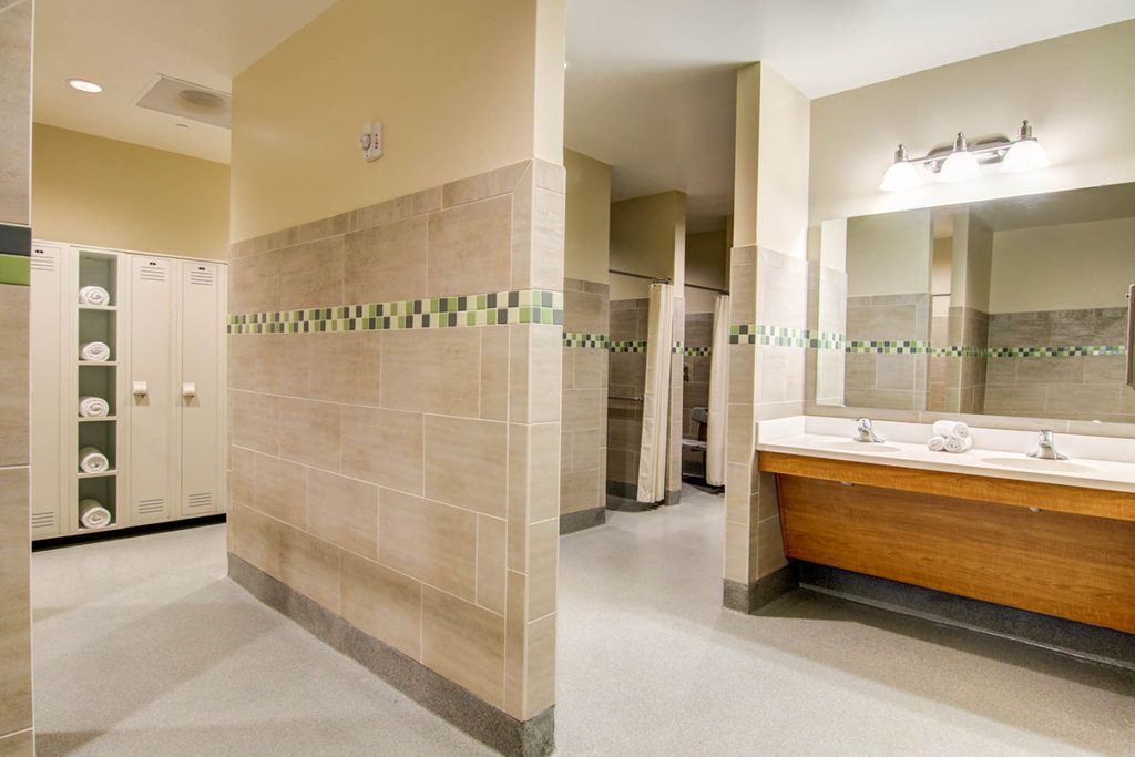 A clean public restroom with tiled walls, sinks, mirrors, and stalls.