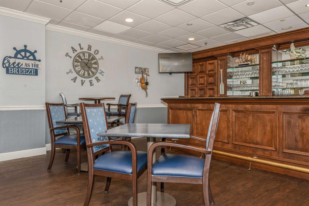 The interior of a tavern featuring wooden tables and chairs, a wall-mounted television, and decorative elements.