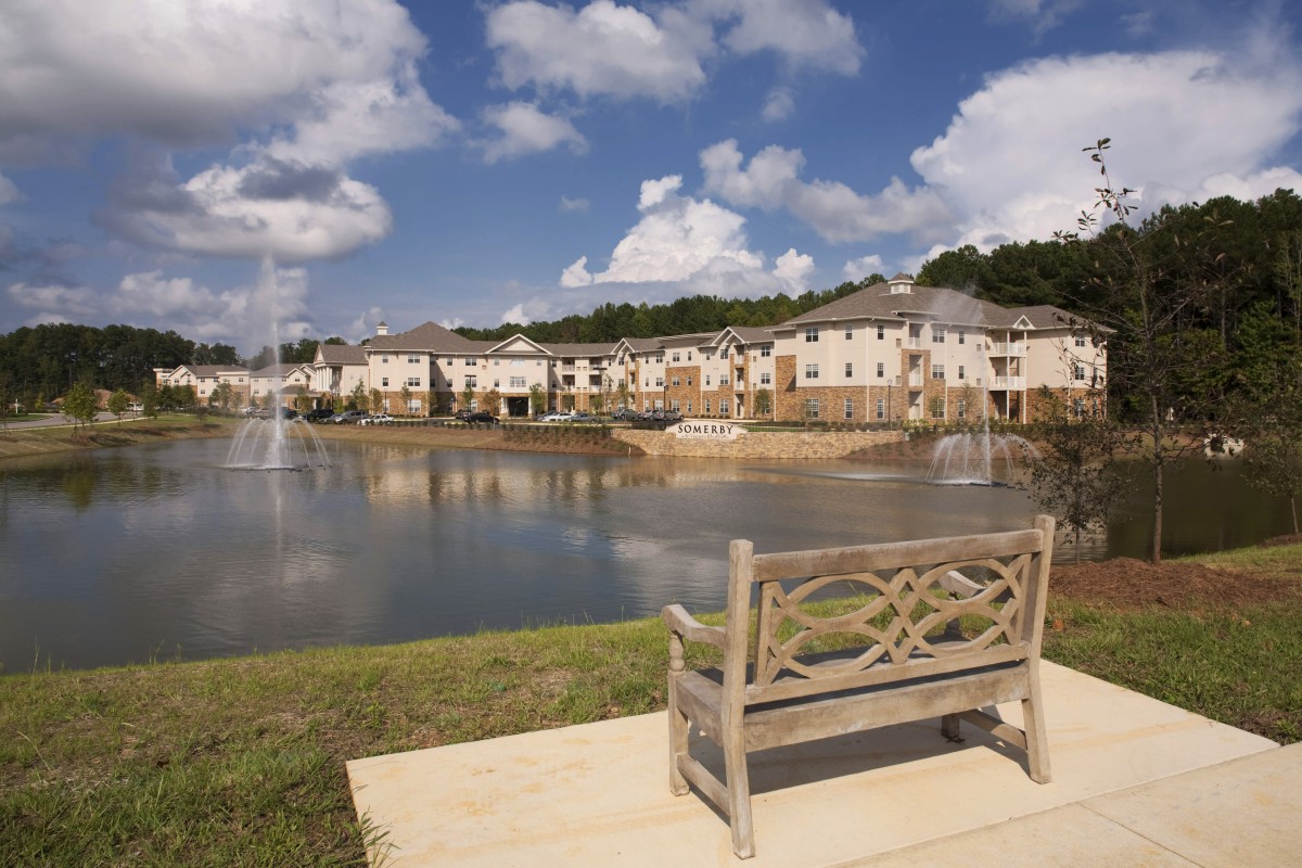 A scenic view of a residential area with a lake and a wooden bench.