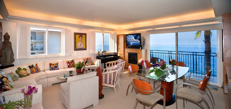 A modern living room with a stunning sea view, stylish furniture, and vibrant artwork.