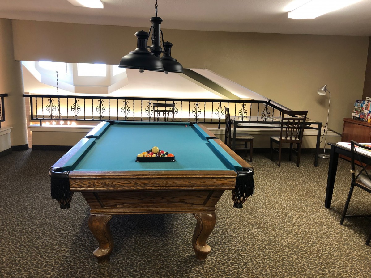 A pool table setup in a well-lit game room.